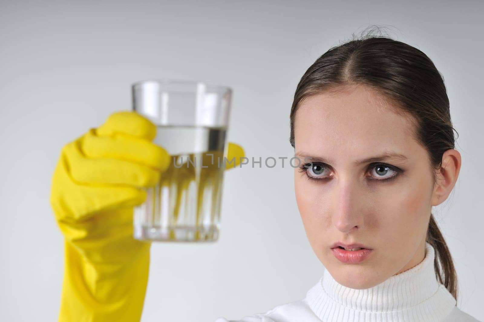 Young woman in yellow hygienic gloves holding glass of water - concentration