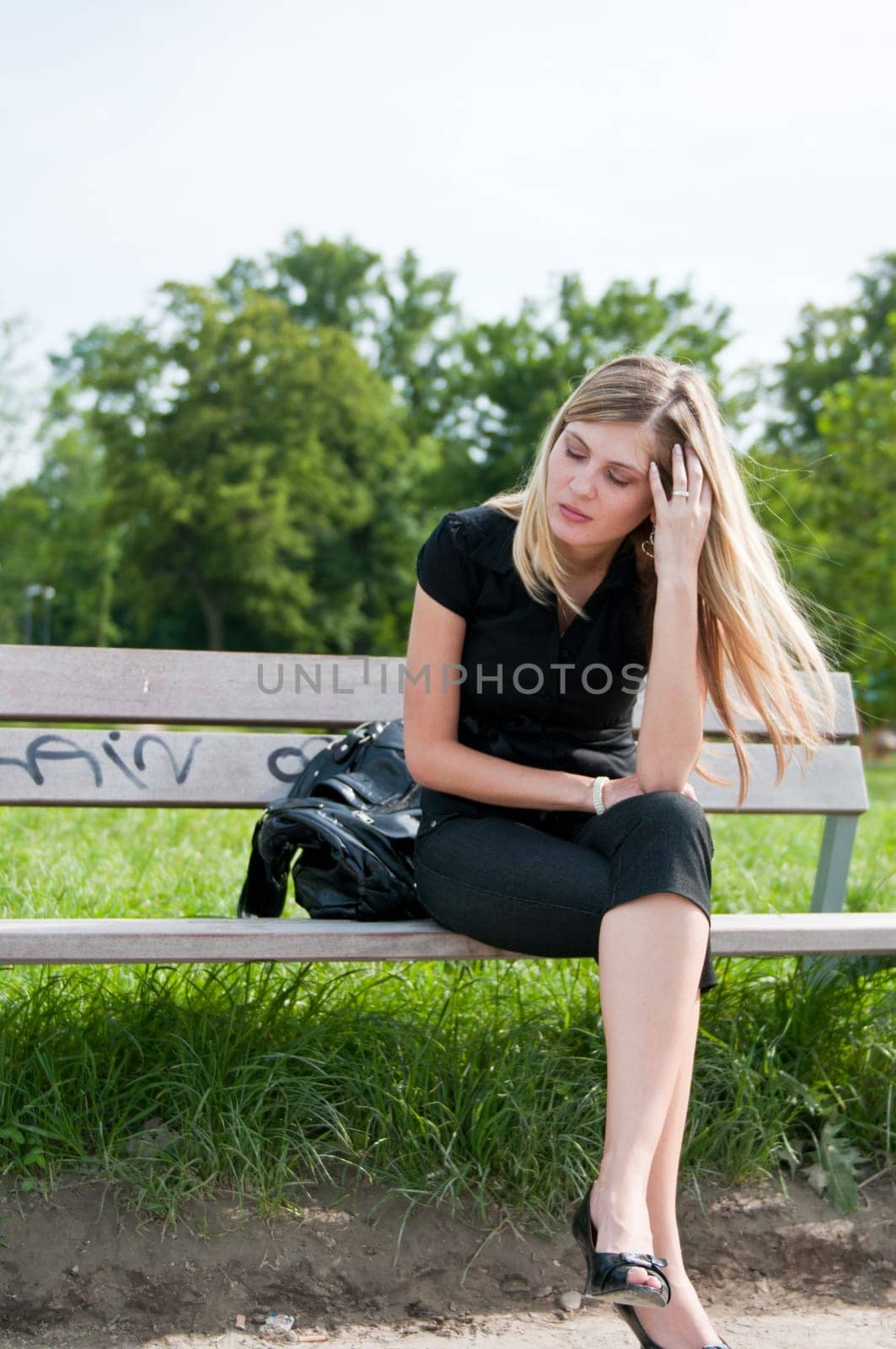 Young beautiful woman siting on bench in park in depression
