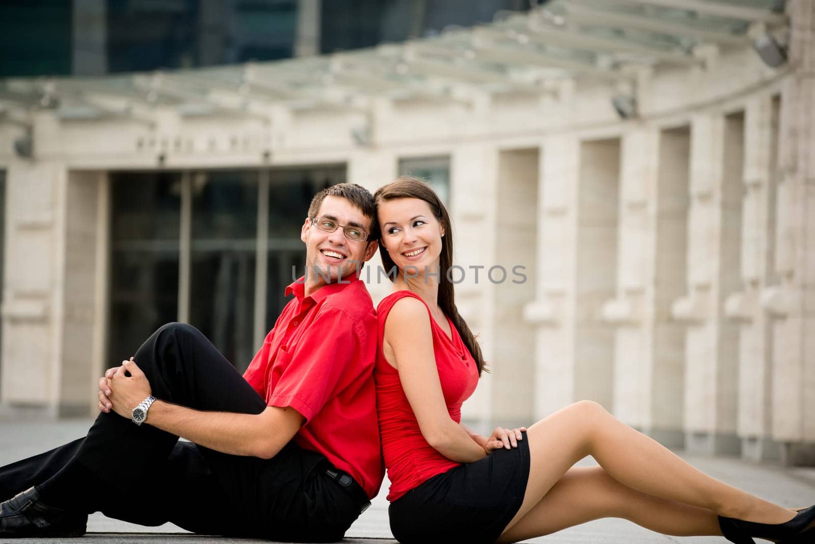 Young business couple relaxing leant with backs on street