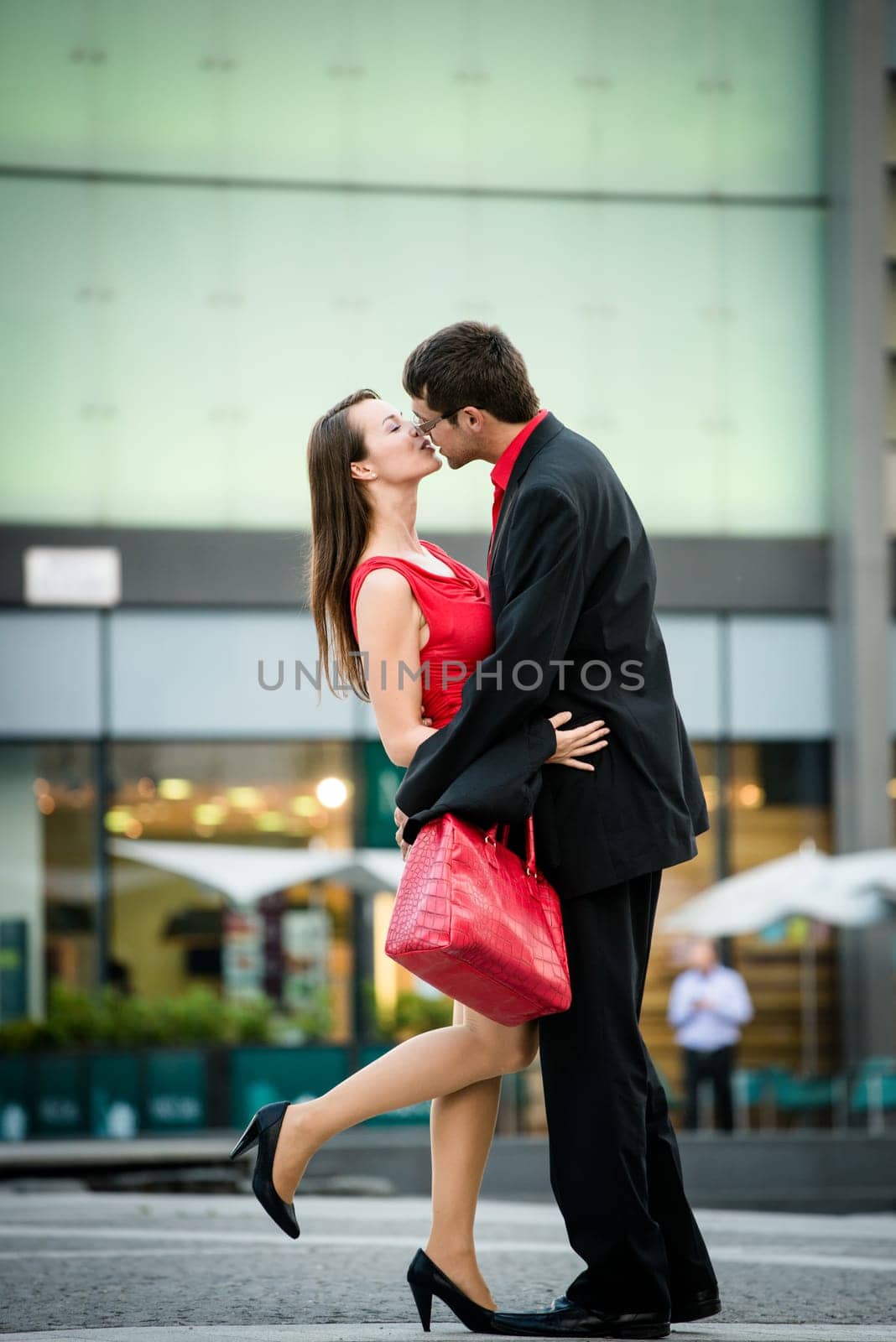 Young business couple dressed in red kiss and welcome each other on street