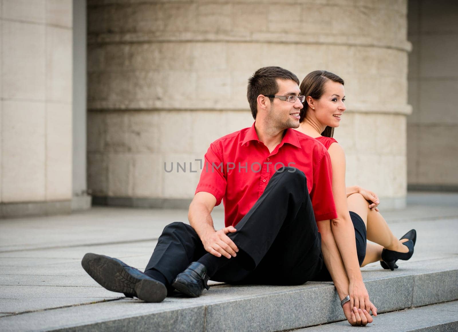 Young business couple relaxing leant with backs on street