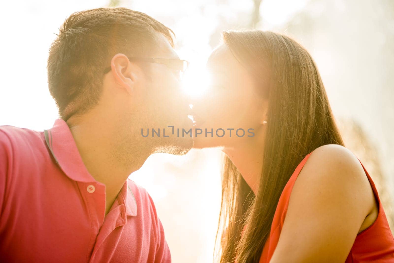Romantic young couple kissing - shot agains direct sun