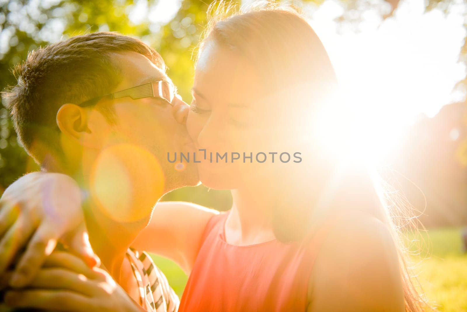 Romantic young couple embracing and kissing at sunset in nature