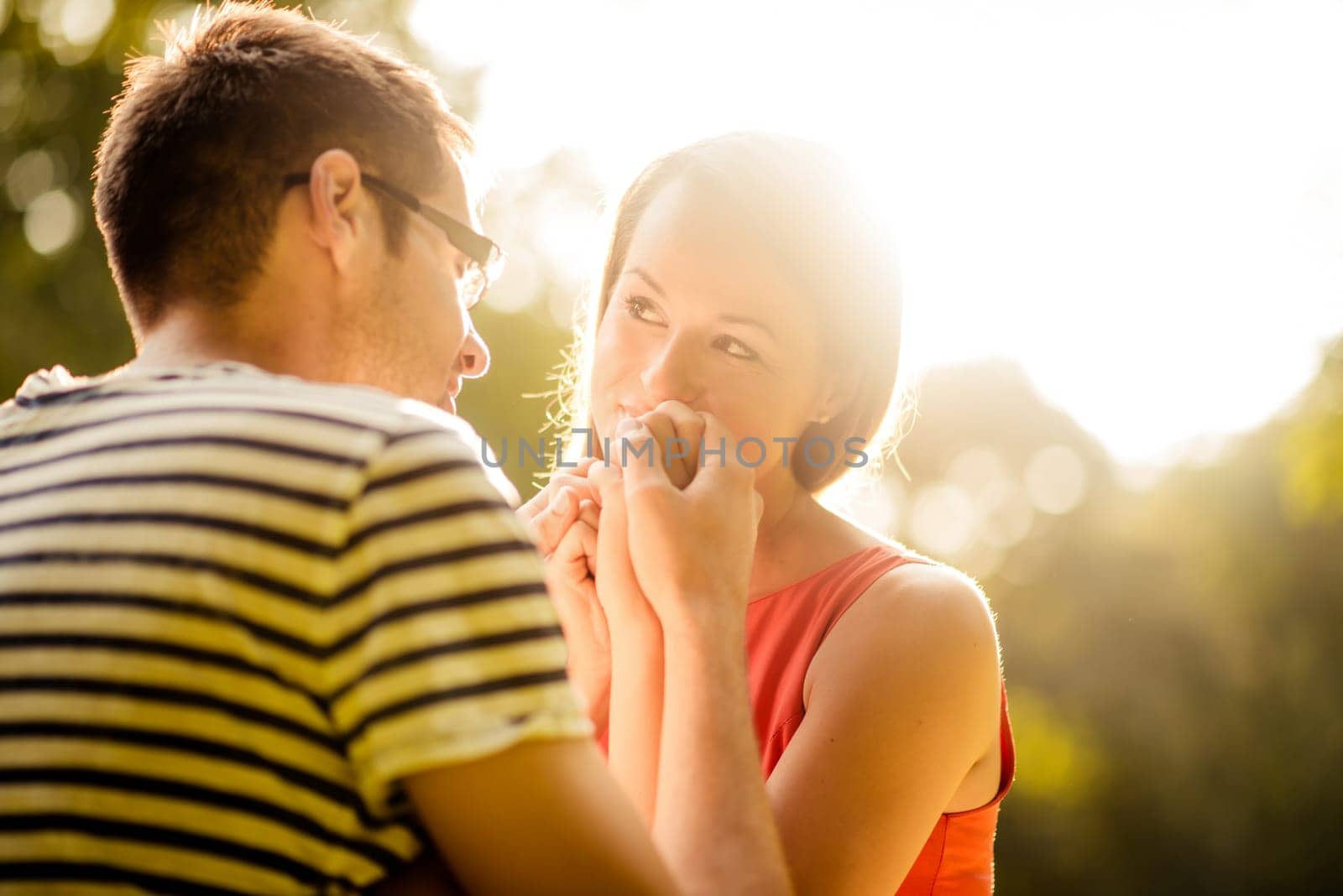 Intimate moments - young couple hugging in nature against sun