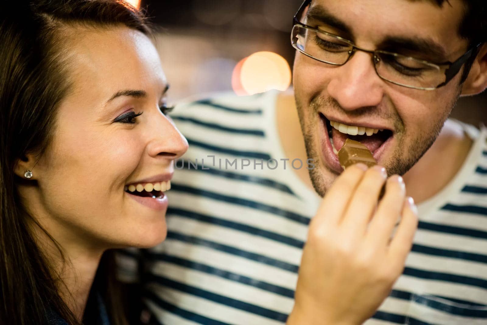 Couple on date - woman feeds her boyfriend with chocolate on street at night
