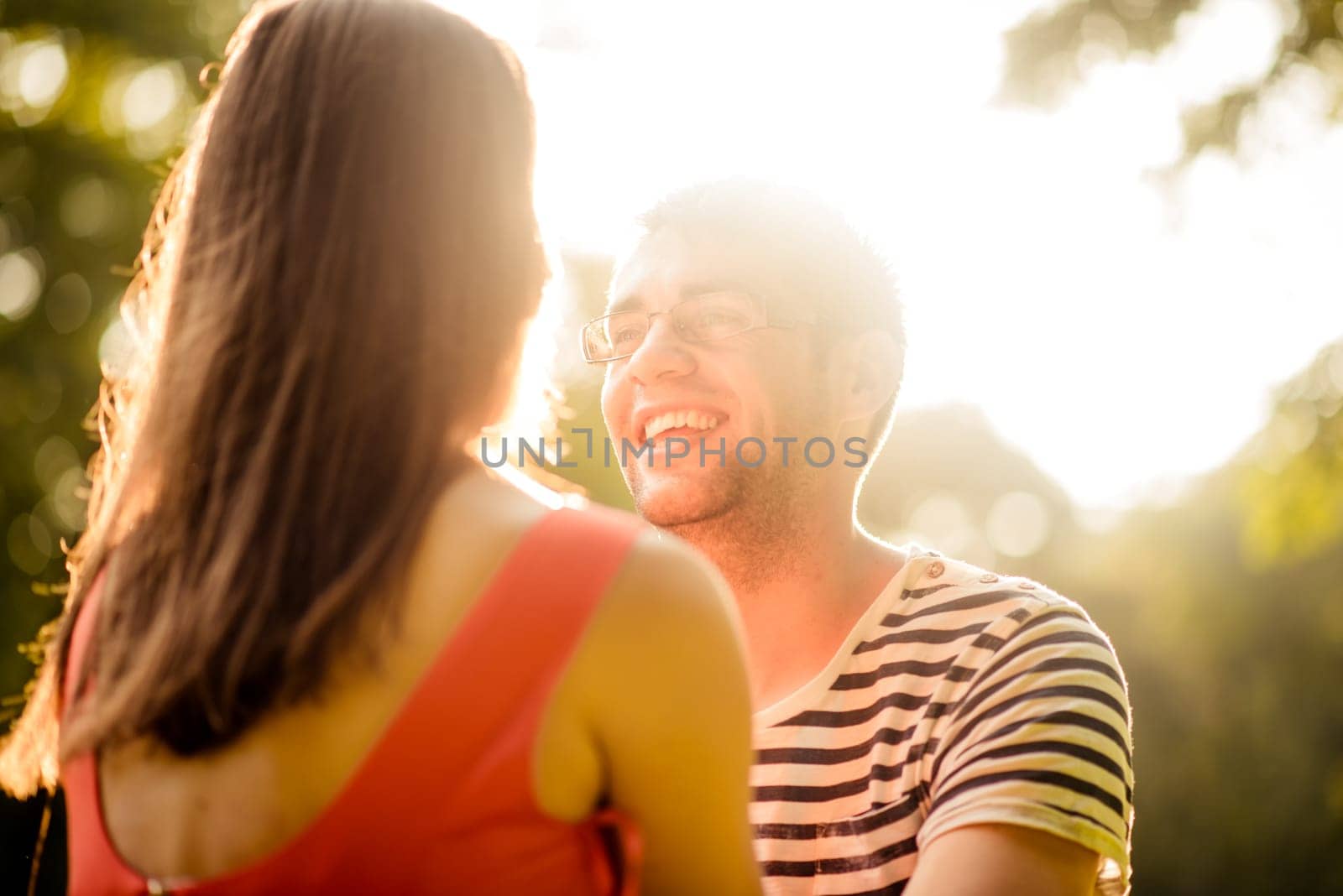 Young happy couple sitting on grass in nature and talking