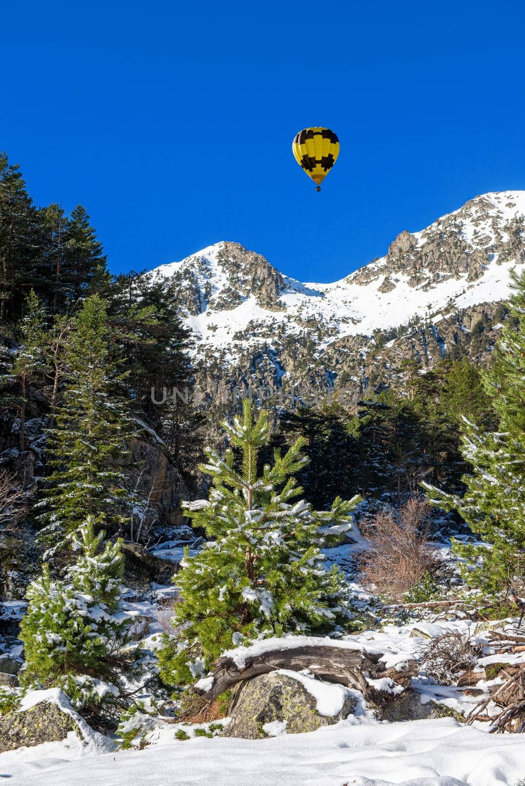 the snowy Pyrenees mountains with a yellow hot air balloon