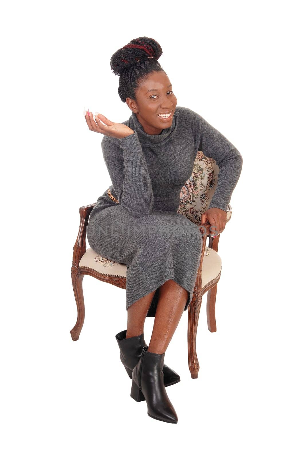 A gorgeous African American woman in a long gray dress sitting in an.old armchair, isolated for white background.