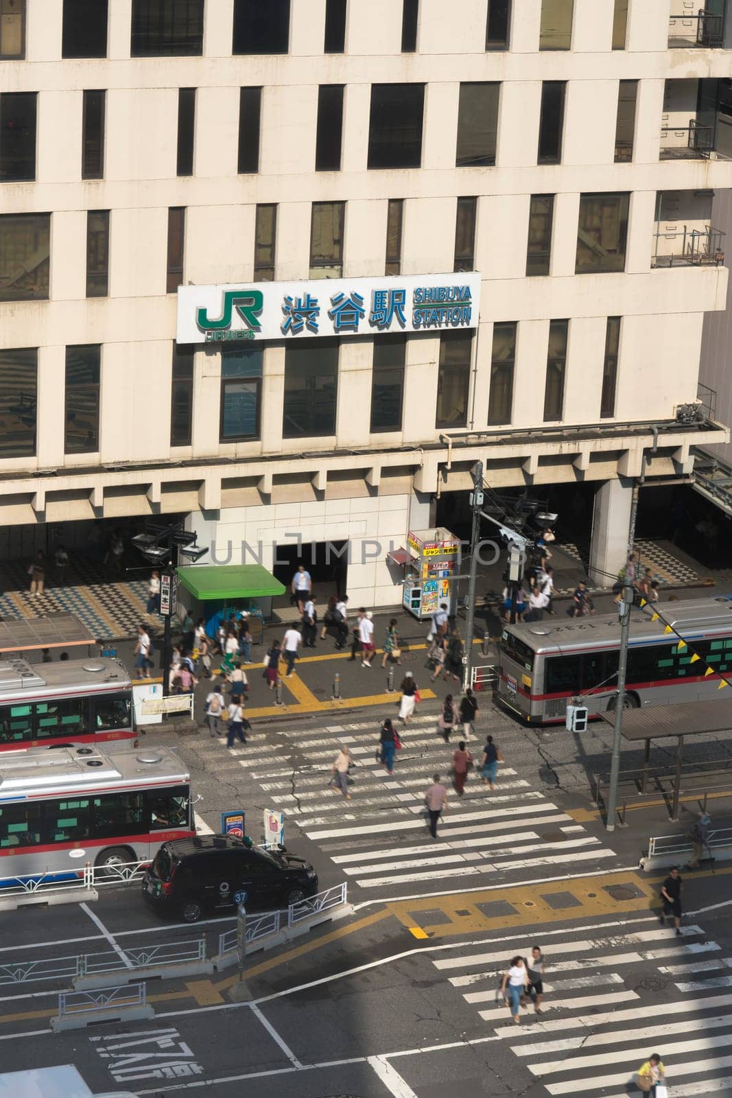 View of the southern exit of Shibuya Station, famous for its moai statue, with buses and taxis stopped at the bus terminal