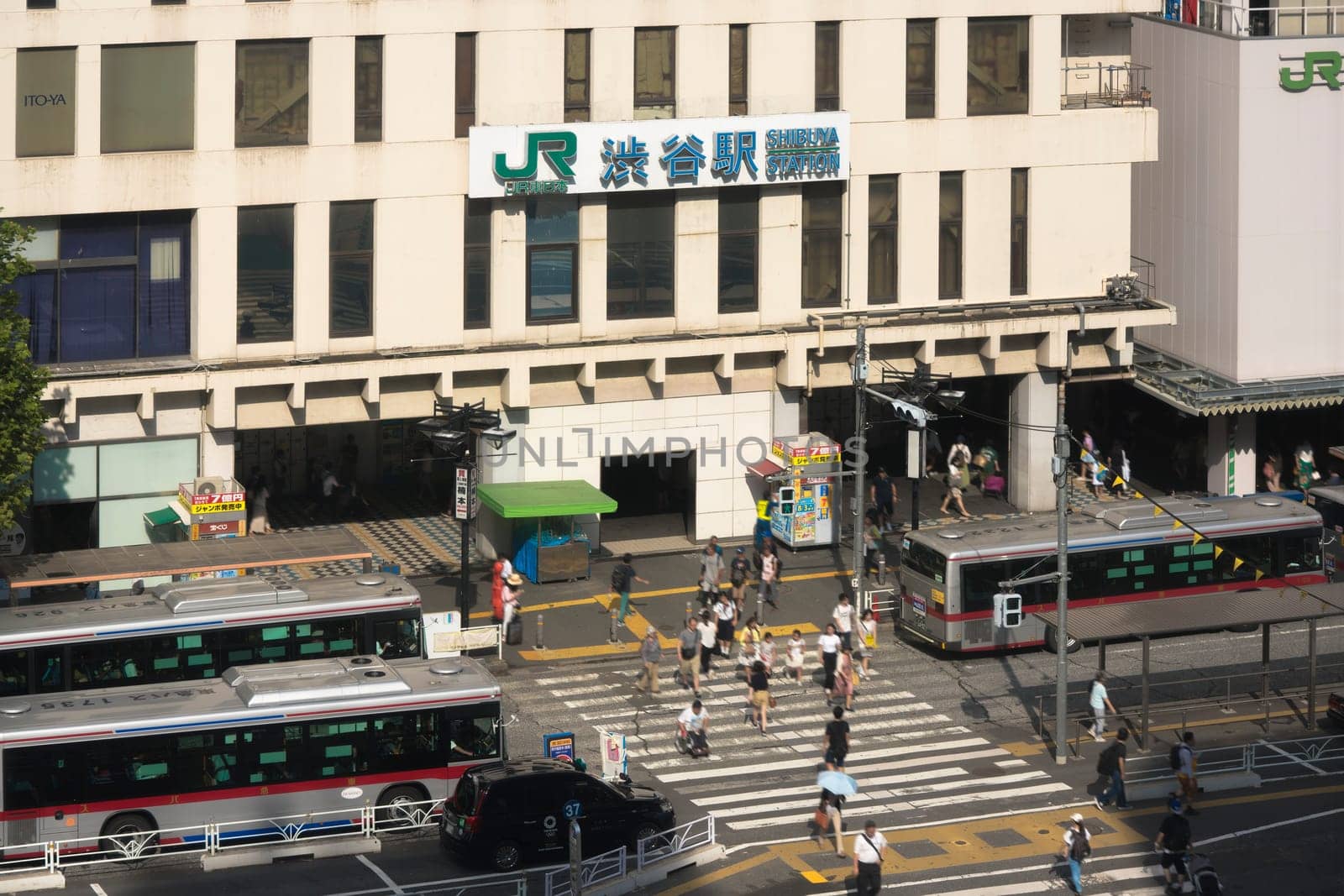 View of the southern exit of Shibuya Station, famous for its moai statue, with buses and taxis stopped at the bus terminal
