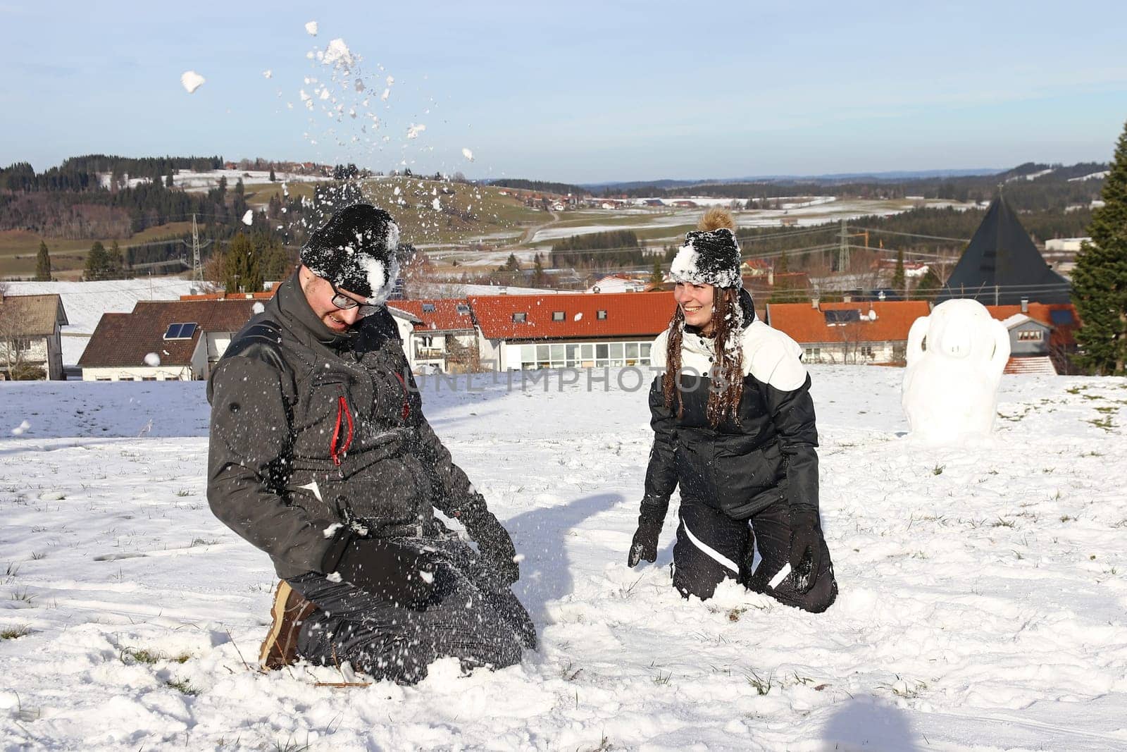 A young couple have a snowball fight in winter. A woman and a man have fun in the snow