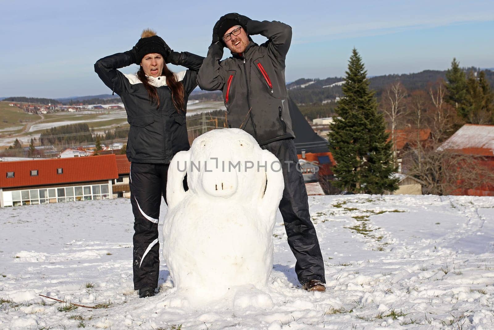 A couple have built a snowman. A woman and a man built an Enton out of snow