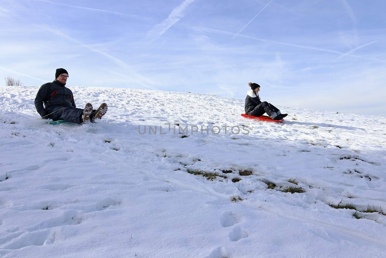A woman and a man riding a snowmobile down a mountain in winter