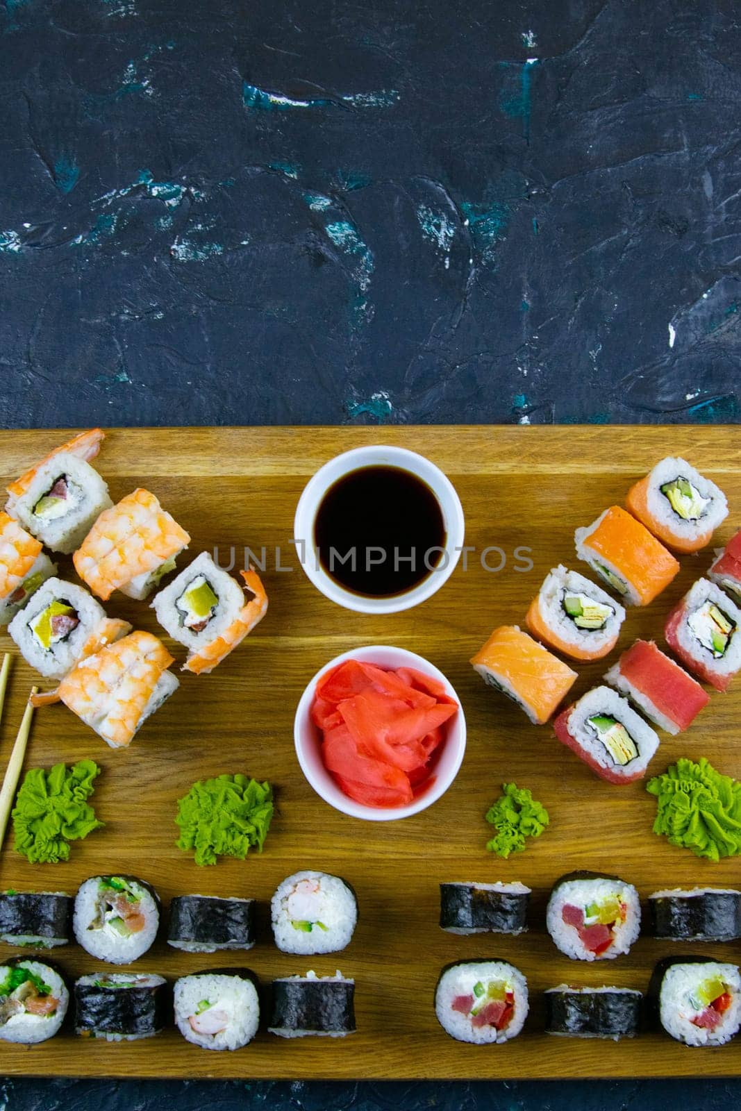 Top view of wooden platter with great set of delicious Nigiri sushi and Tempura rolls with Maki and Uramaki rolls on an orange background. Front views