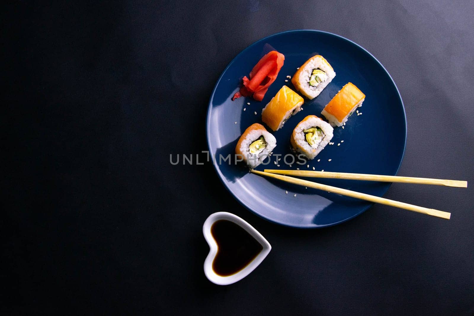 Top view of wooden platter with great set of delicious Nigiri sushi and Tempura rolls with Maki and Uramaki rolls on an orange background. Front views