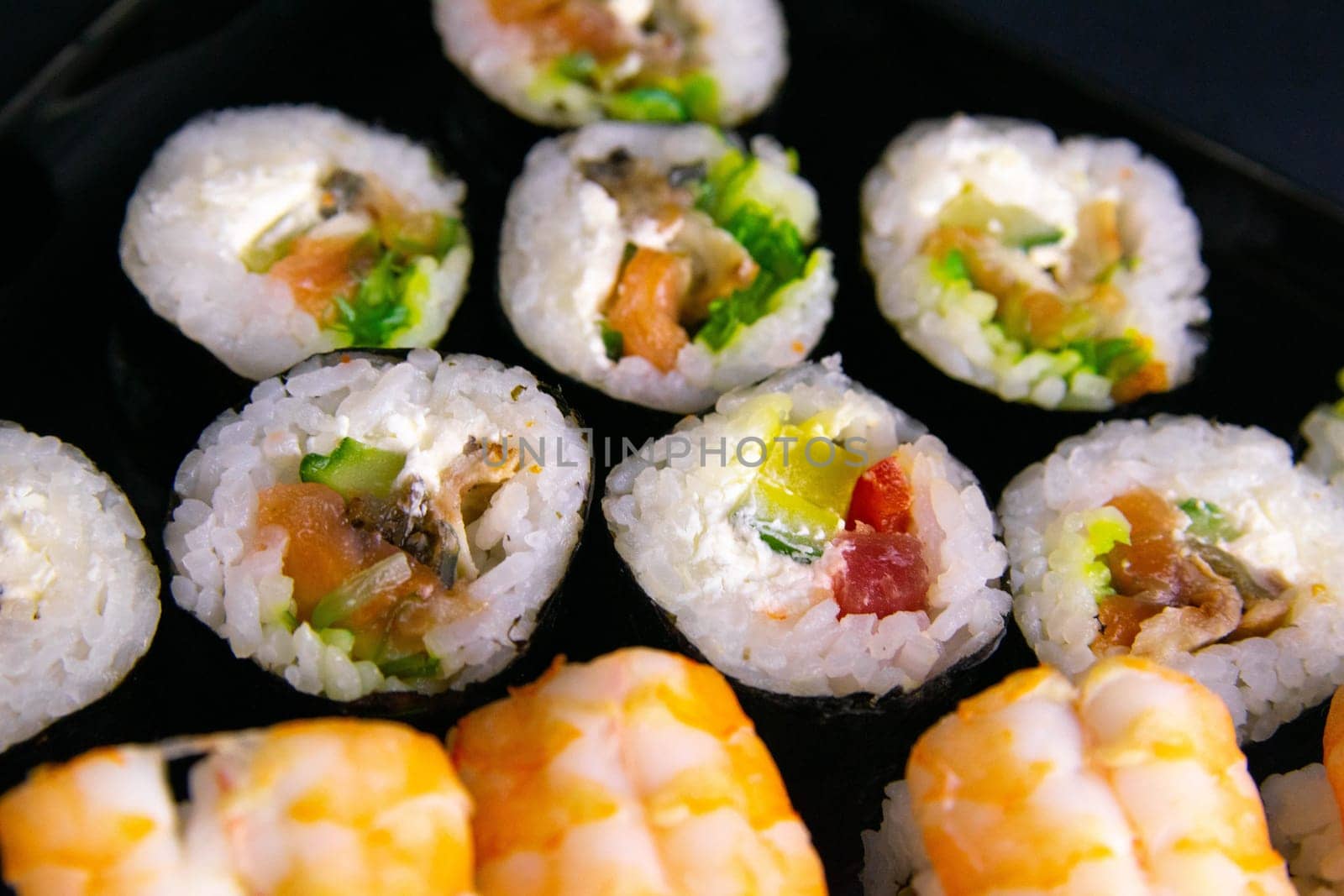 Top view of wooden platter with great set of delicious Nigiri sushi and Tempura rolls with Maki and Uramaki rolls on an orange background. Front views