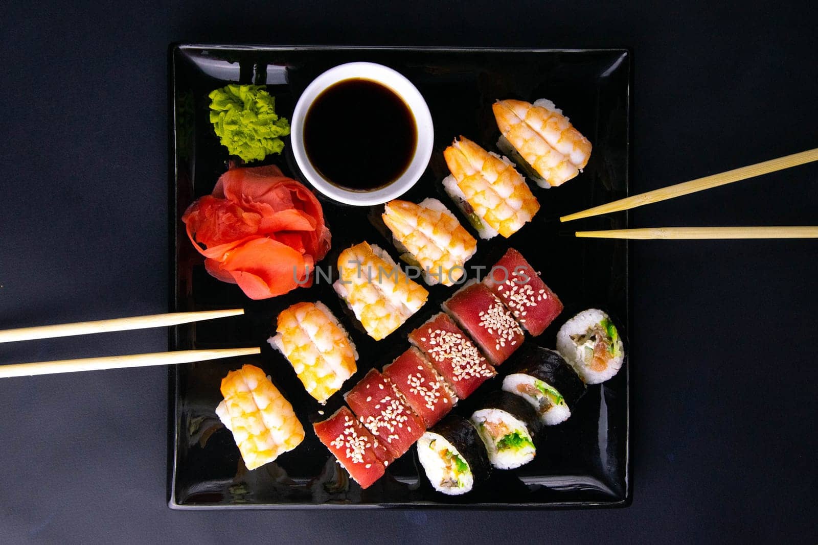 Top view of wooden platter with great set of delicious Nigiri sushi and Tempura rolls with Maki and Uramaki rolls on an rad background. Top views