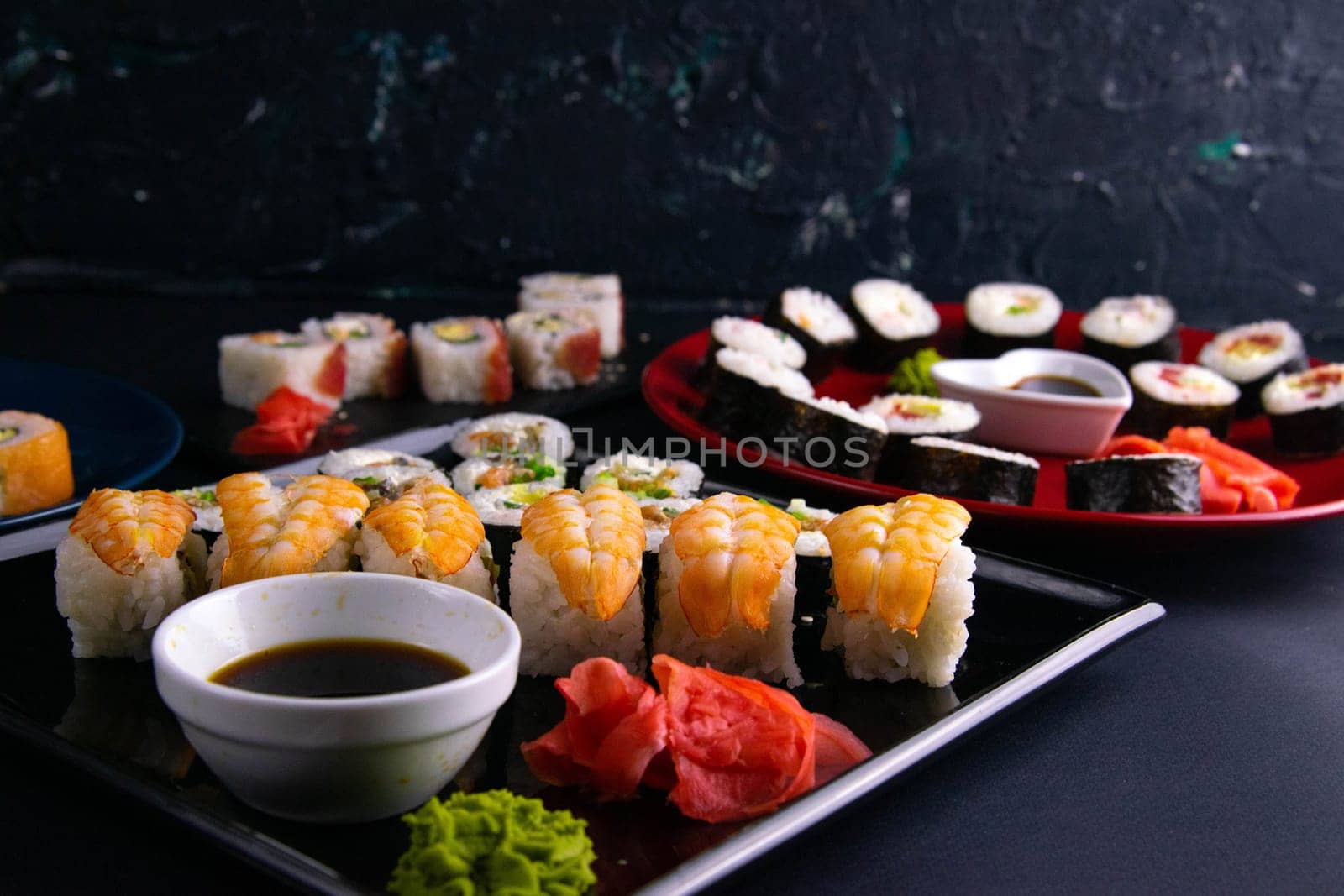 Top view of wooden platter with great set of delicious Nigiri sushi and Tempura rolls with Maki and Uramaki rolls on an orange background. Front views