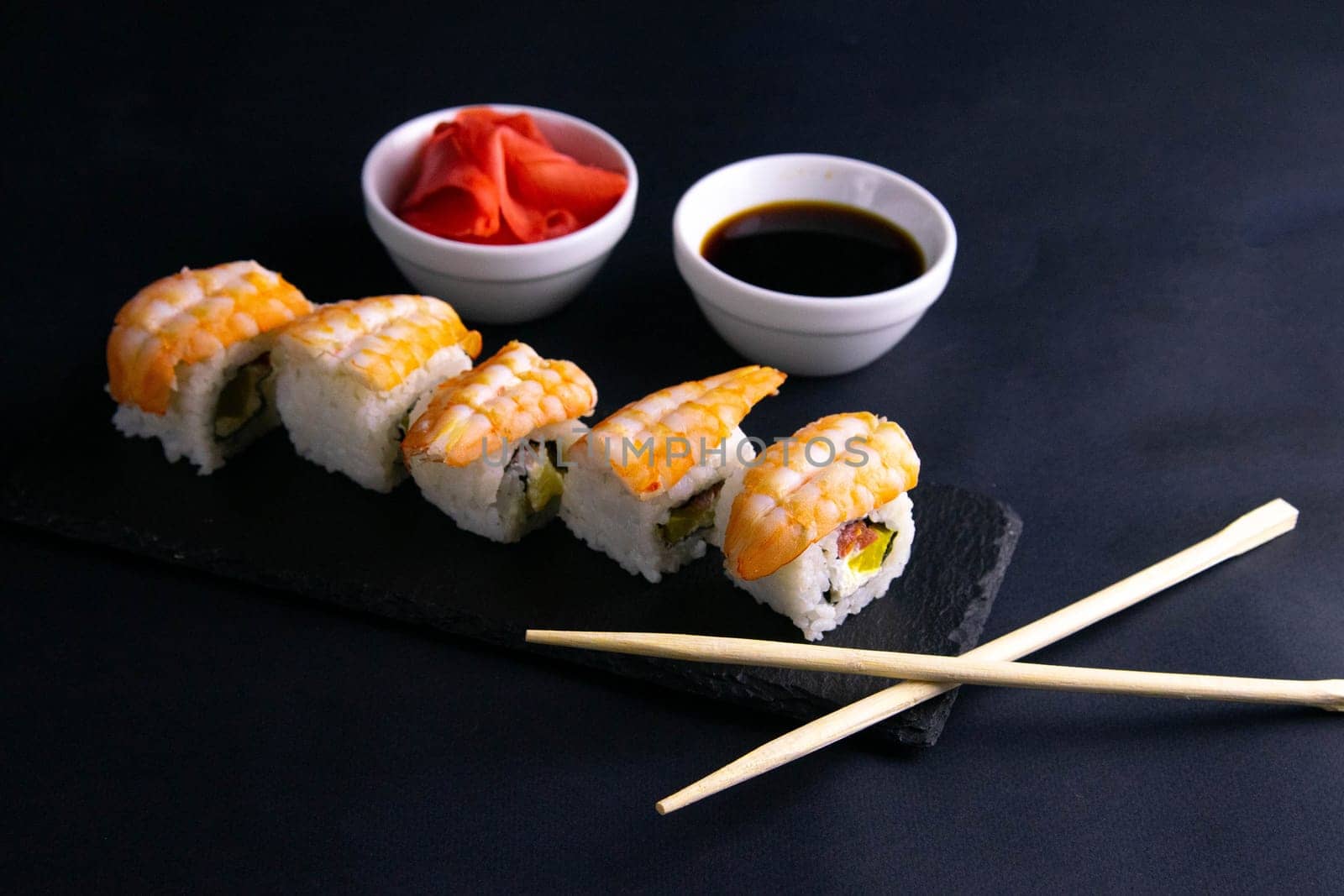 Top view of wooden platter with great set of delicious Nigiri sushi and Tempura rolls with Maki and Uramaki rolls on an rad background. Top views