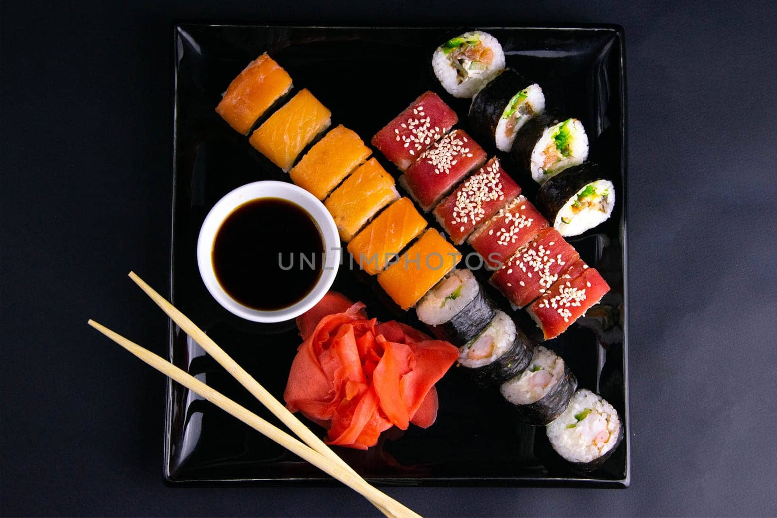 Top view of wooden platter with great set of delicious Nigiri sushi and Tempura rolls with Maki and Uramaki rolls on an rad background. Top views