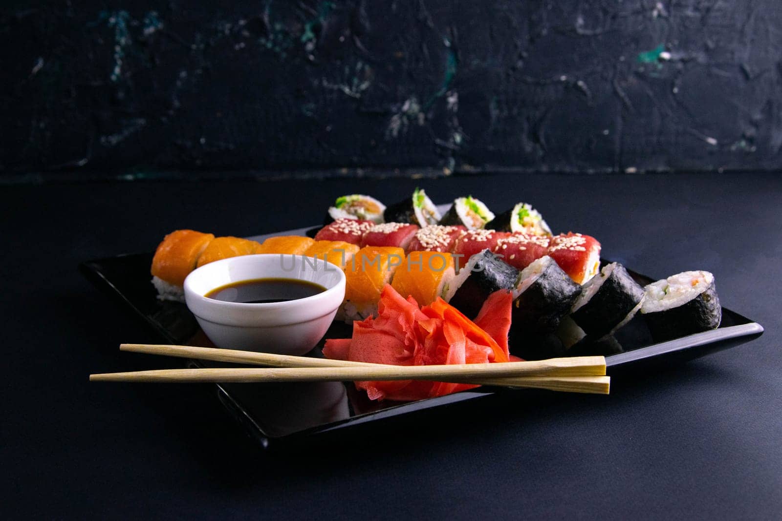 Top view of wooden platter with great set of delicious Nigiri sushi and Tempura rolls with Maki and Uramaki rolls on an rad background. Top views