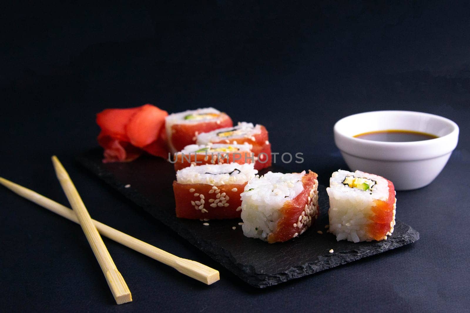 Top view of wooden platter with great set of delicious Nigiri sushi and Tempura rolls with Maki and Uramaki rolls on an rad background. Top views