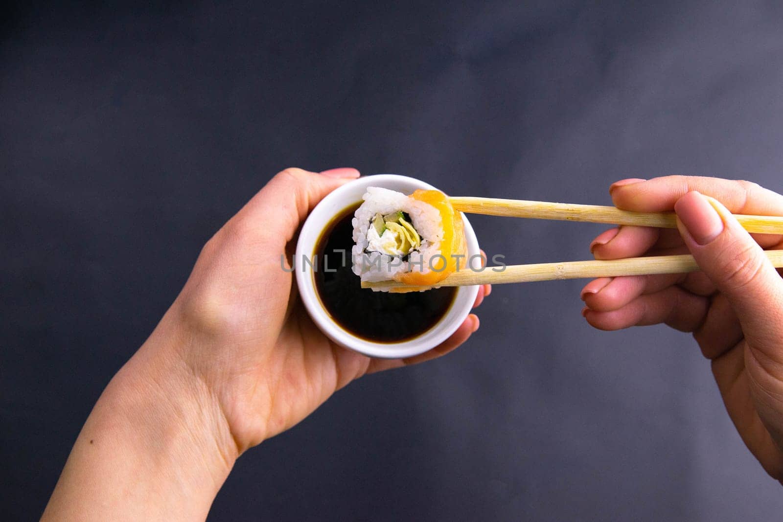 Sticks to reach for the roll, roll in the piece of packaging, next to the role of pickled ginger, everything stands on a red background. Top views