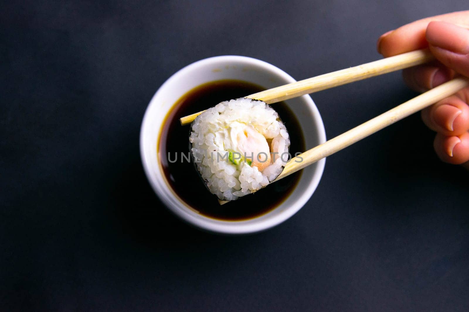 Sticks to reach for the roll, roll in the piece of packaging, next to the role of pickled ginger, everything stands on a red background. Top views