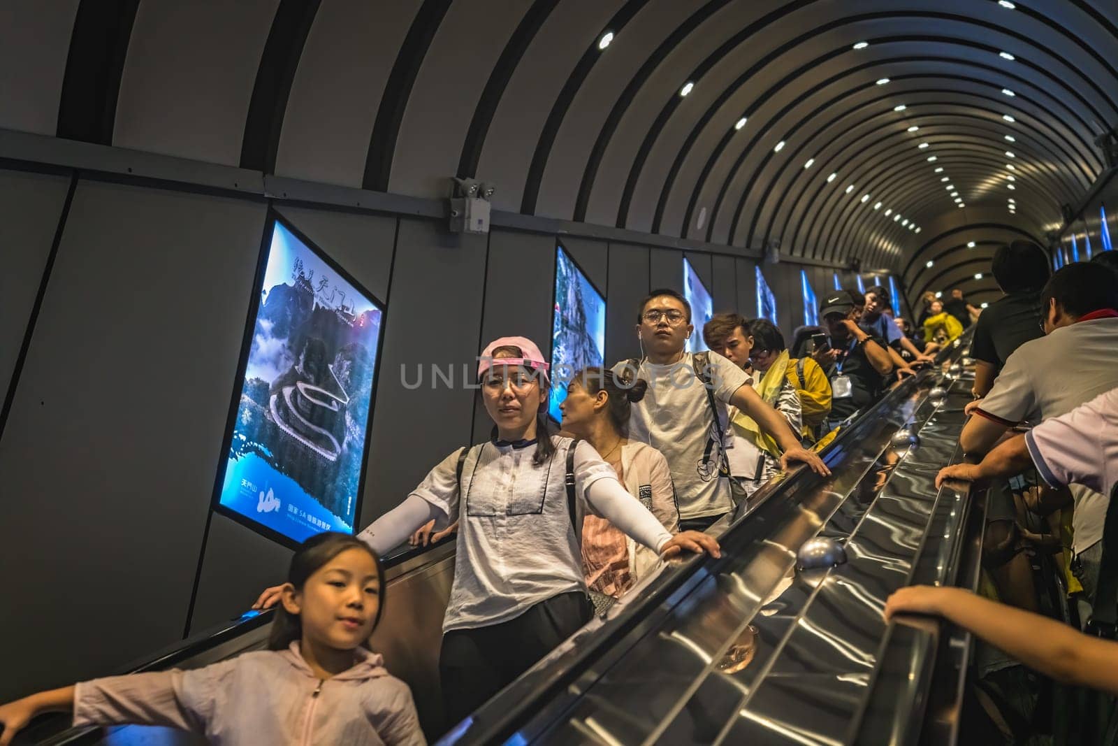 Zhangjiajie, China - August 2019 : Crowd of people transported via moving stair escalator cut inside the rock to the top of the famou Tianmen Shan mountain