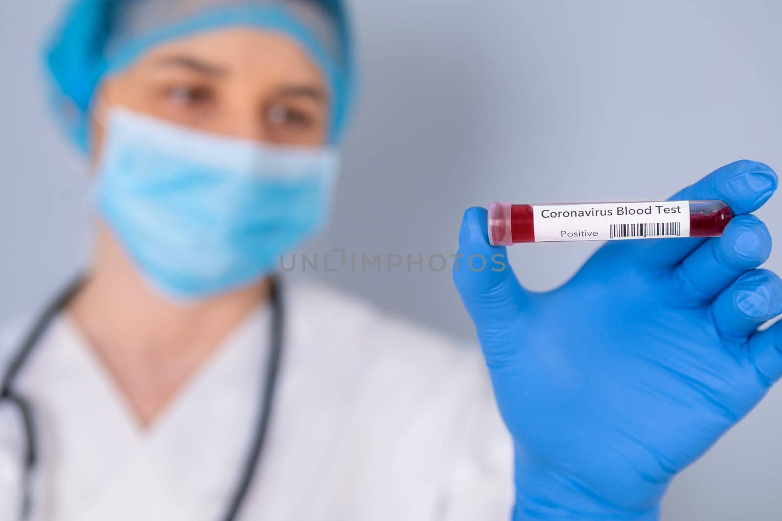 Nurse holding test tube with Positive Coronavirus test blood sample. Virus test and research concept. Focus is on blood test tube.