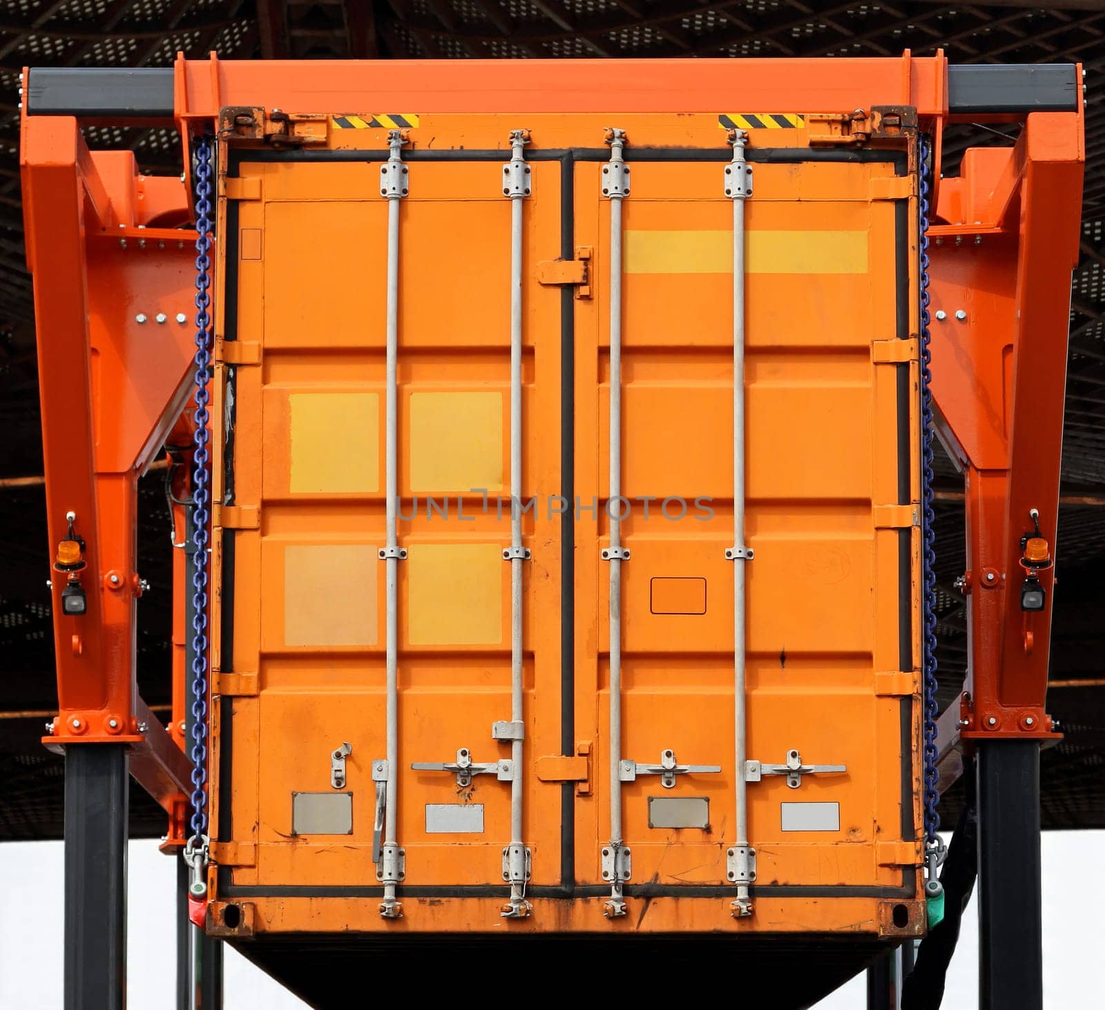 Lifting up orange cargo container in warehouse