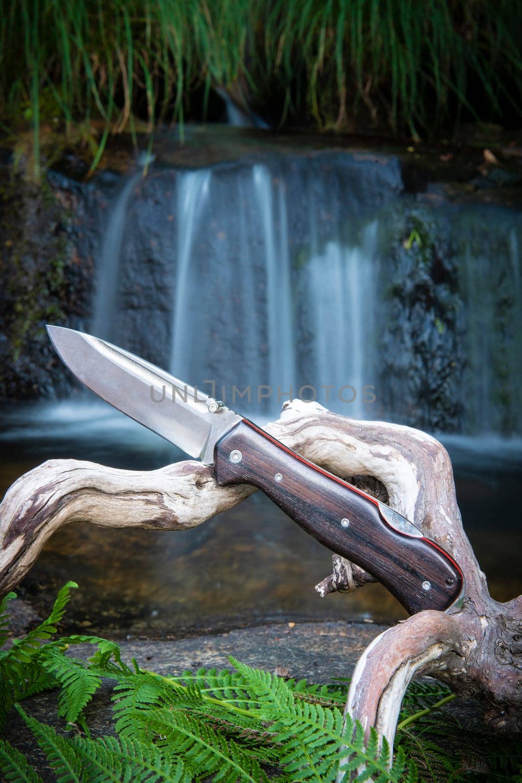 knife for bushcraft and survival in the wild near to a waterfall