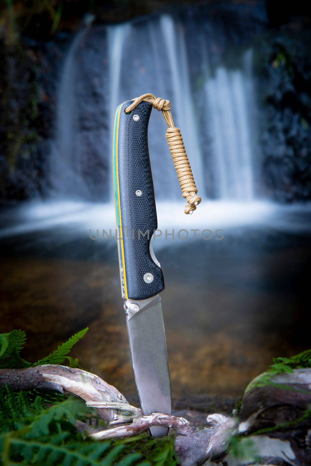knife for bushcraft and survival in the wild near to a waterfall