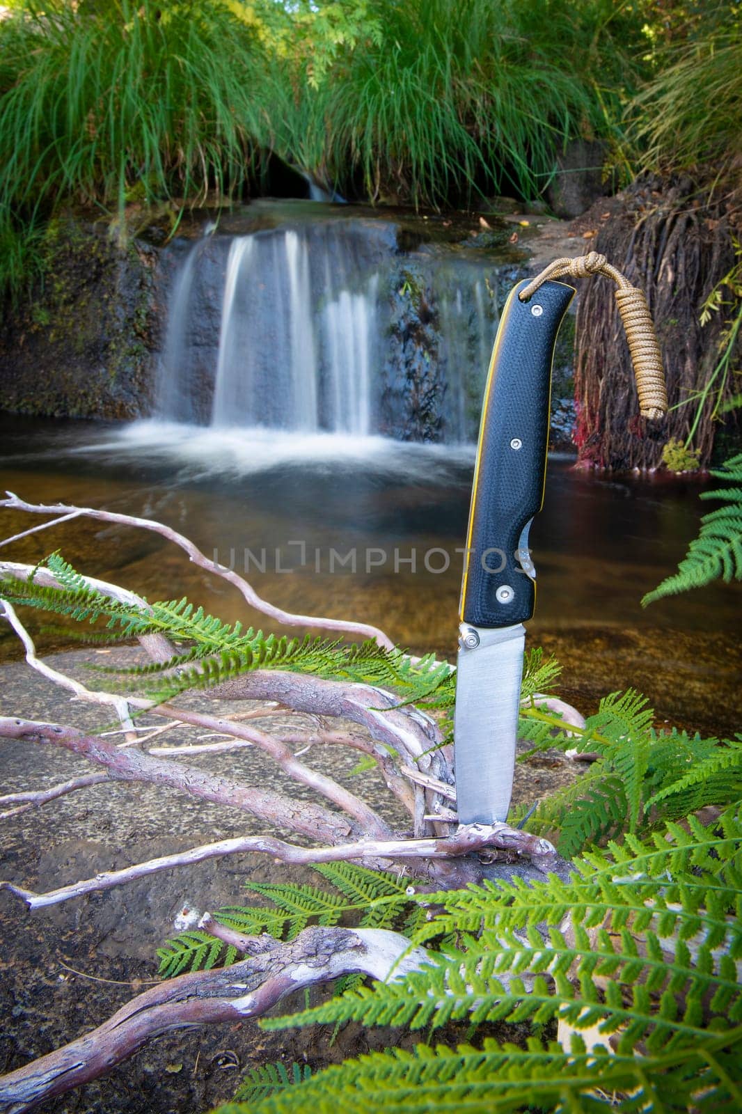 knife for bushcraft and survival in the wild near to a waterfall