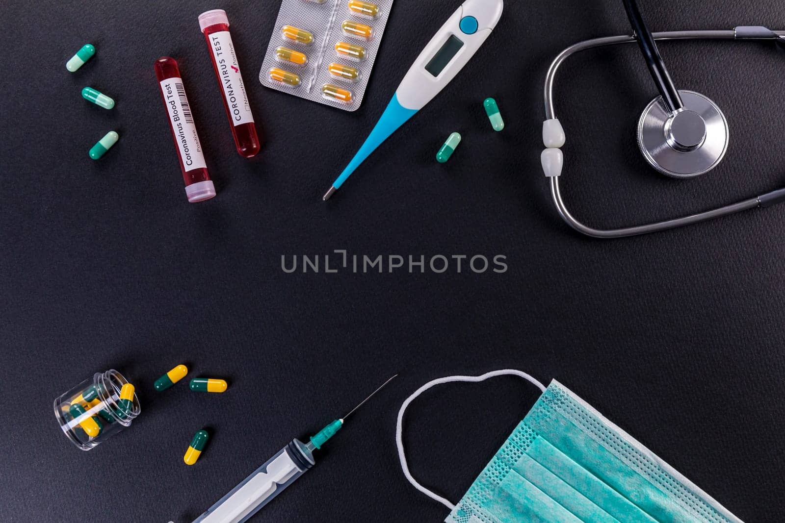 Blood test tube with the Coronavirus disease for virus test and research. Blood test tube with protective masks, medicines, thermometer, stethoscope and syringe on a black background.