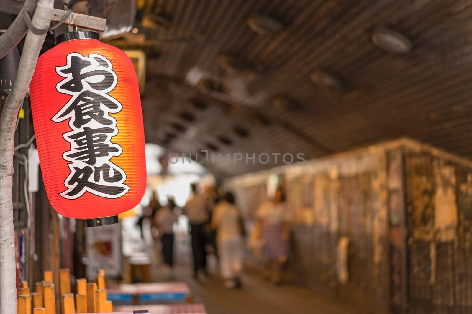 Traditional retro red rice paper lantern where it is written "Oshokujidokoro"" which means ""Meal"" on underpass Yurakucho Concourse wall under the railway line of the station Yurakucho. Japanese noodle stalls and sake bars revive the nostalgic years of Showa air with old posters and placards glued to the walls of the tunnel."