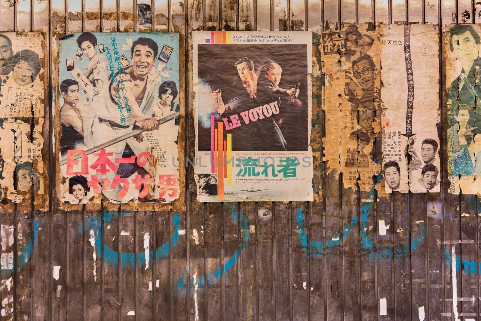 Old vintage retro japanese movie posters on underpass Yurakucho Concourse wall under the railway line of the station Yurakucho. Japanese noodle stalls and sake bars revive the nostalgic years of Showa air with old samurai posters, french nouvelle vague movie poster and placards glued to the walls of the tunnel.