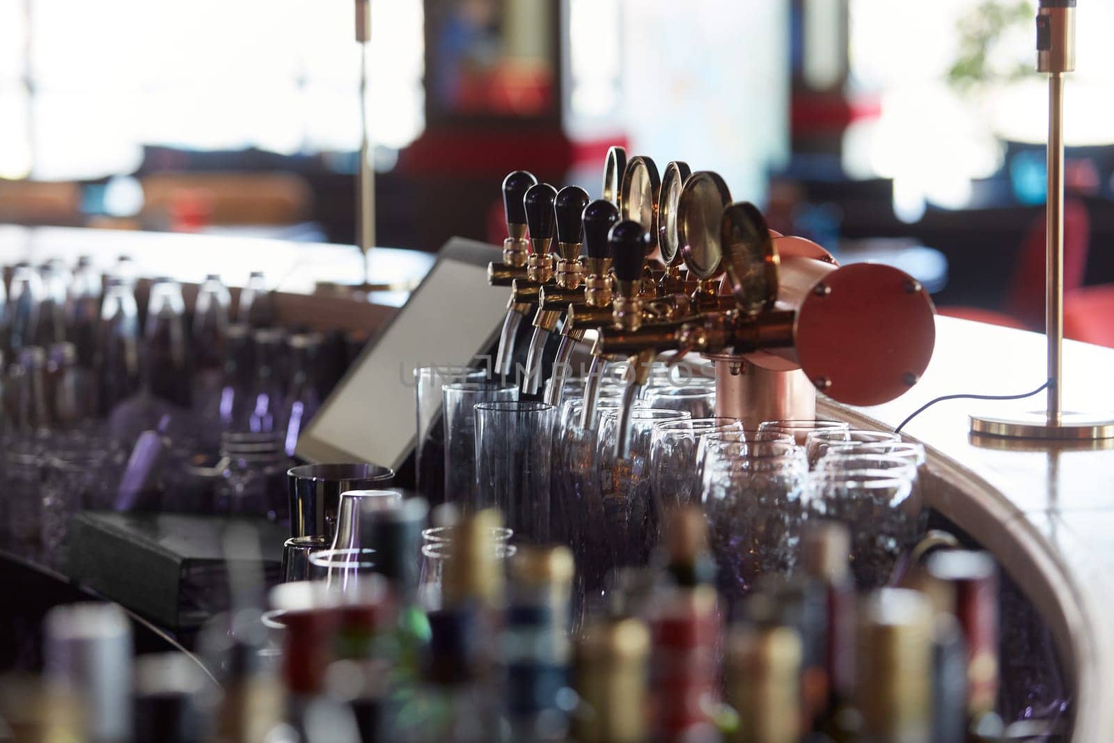 Bar counter with beer taps, glasses and bottles. Interior of pub, nightclub, cafe or restaurant