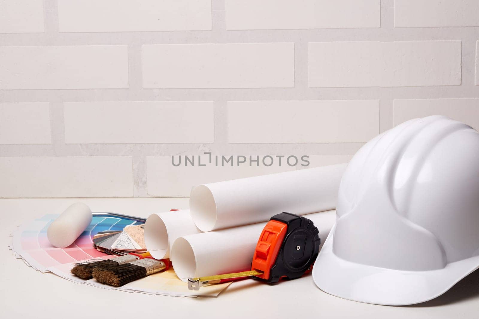 Architectural blueprints, construction hard hat, color palette guide, painting accessories on light background.  Architect workplace. Engineering tools. Concept of construction or design office