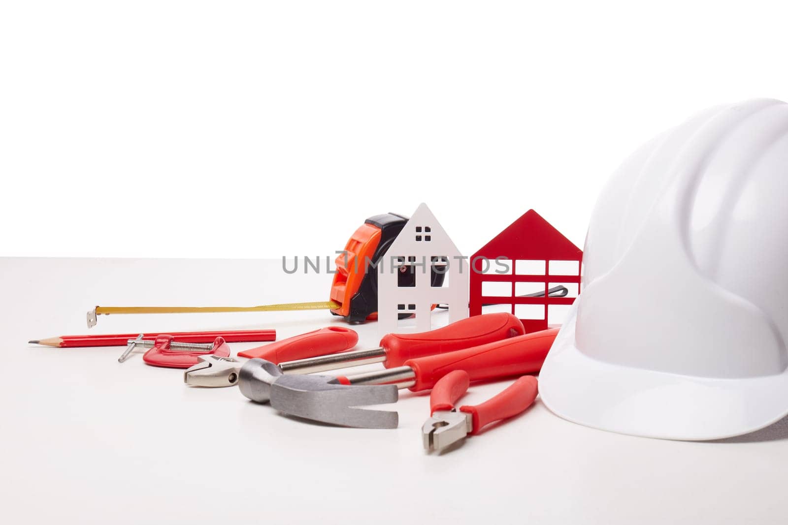 Construction hard hat, various tools and model of house on white background. Concept of construction