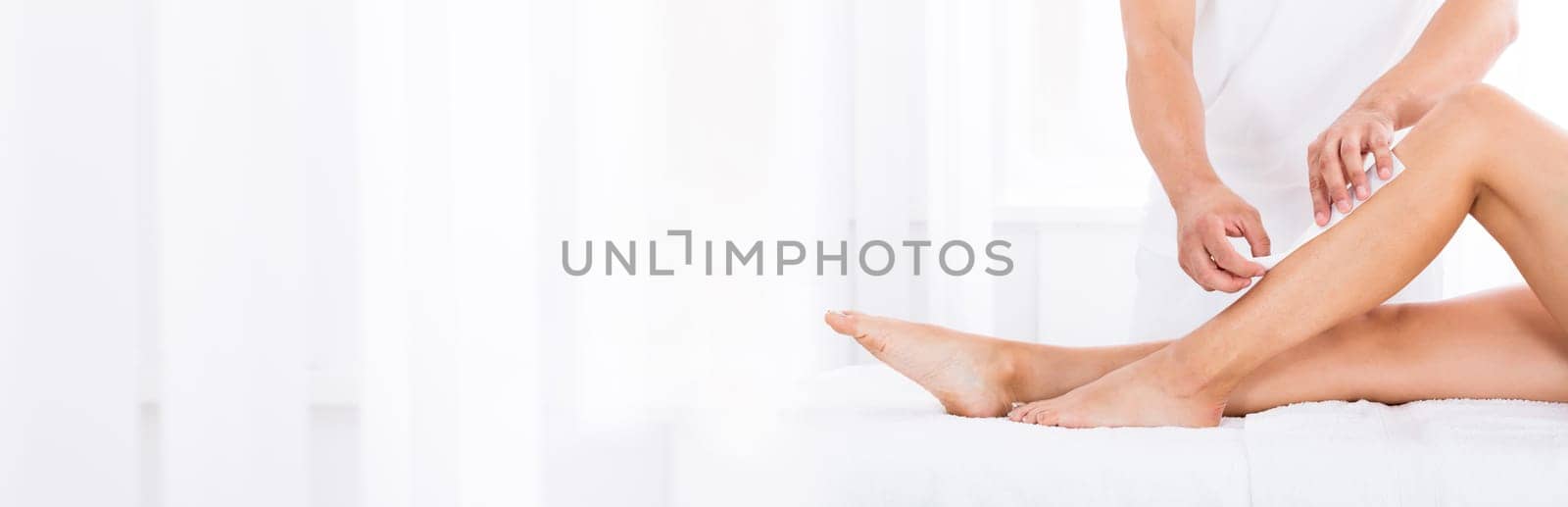 Close-up Of A Beautician Waxing Woman's Leg In Beauty Spa