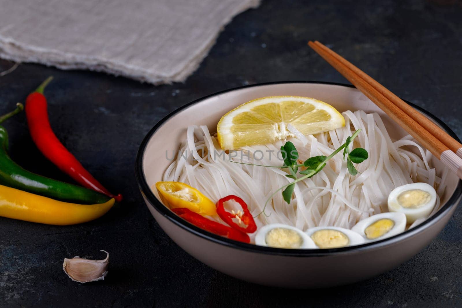 Rice noodles Asian cuisine with quail eggs, chili pepper and lemon, and green pea sprout