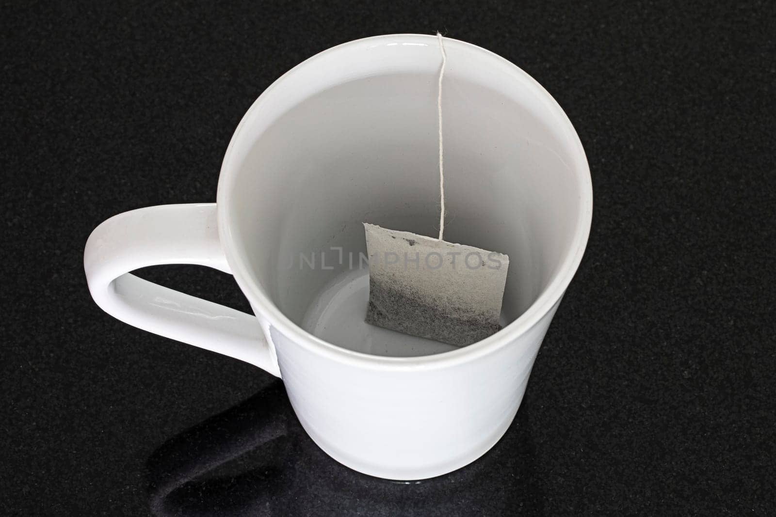 white mug black background tea bag closeup object single
