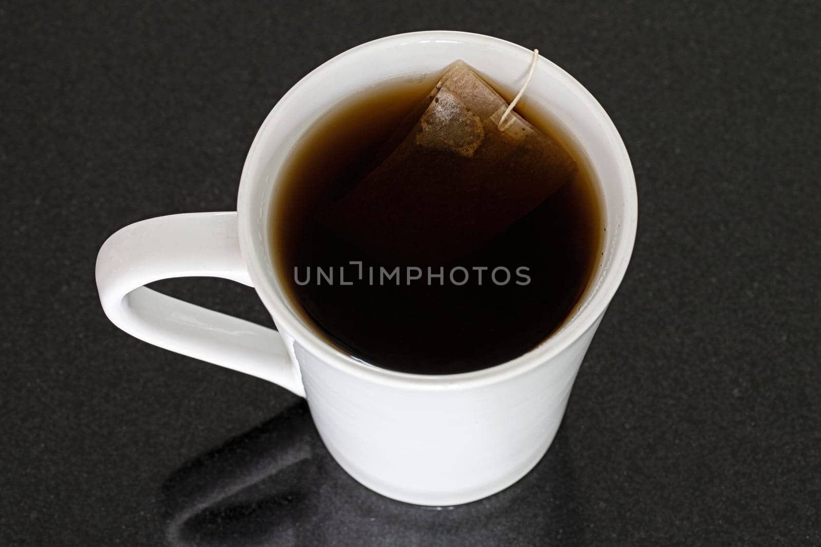 white mug black background tea bag liquid closeup object single