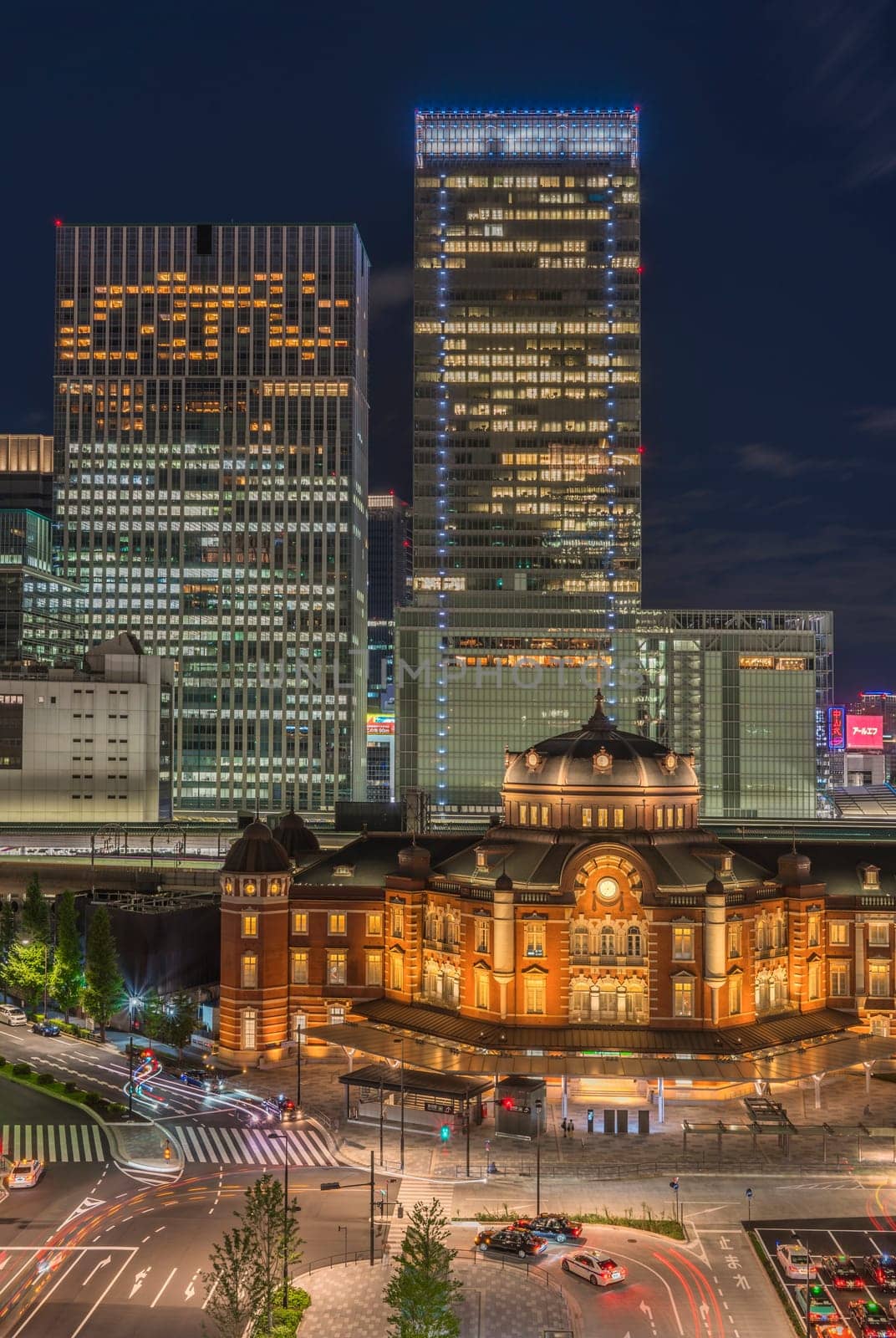 Marunouchi side of Tokyo railway station in the Chiyoda City, Tokyo, Japan.  The station is divided into Marunouchi and Yaesu sides in its directional signage. The station first called Central Station was built in 1914 directly in front of the Imperial Palace gardens. The three-story station building was designed by architect Tatsuno Kingo who also designed Manseibashi Station and the nearby Bank of Japan building. Much of the station was destroyed in B-29 firebombing on May 25, 1945. The bombing shattered the impressive rooftop domes. The station was quickly rebuilt within the year, but simple angular roofs were built in place of the domes, and the restored building was only two stories tall instead of three.