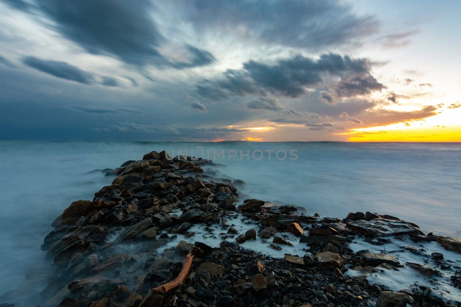 Sea sunset after sunset, in the foreground a breakwater of stones