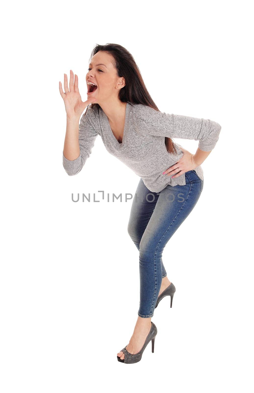 A slim young woman standing bending forwards with one hand on her.mouth, shouting at people, isolated for white background.