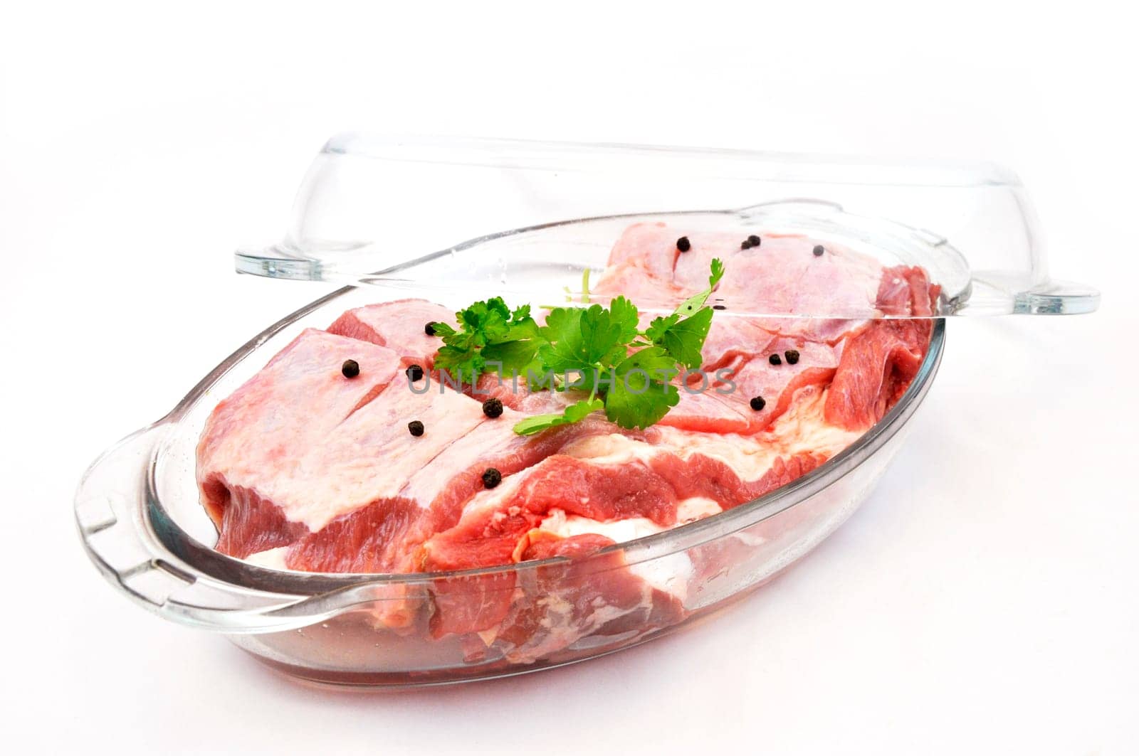 Fresh red meat with seasoning in glass pan ready to cook