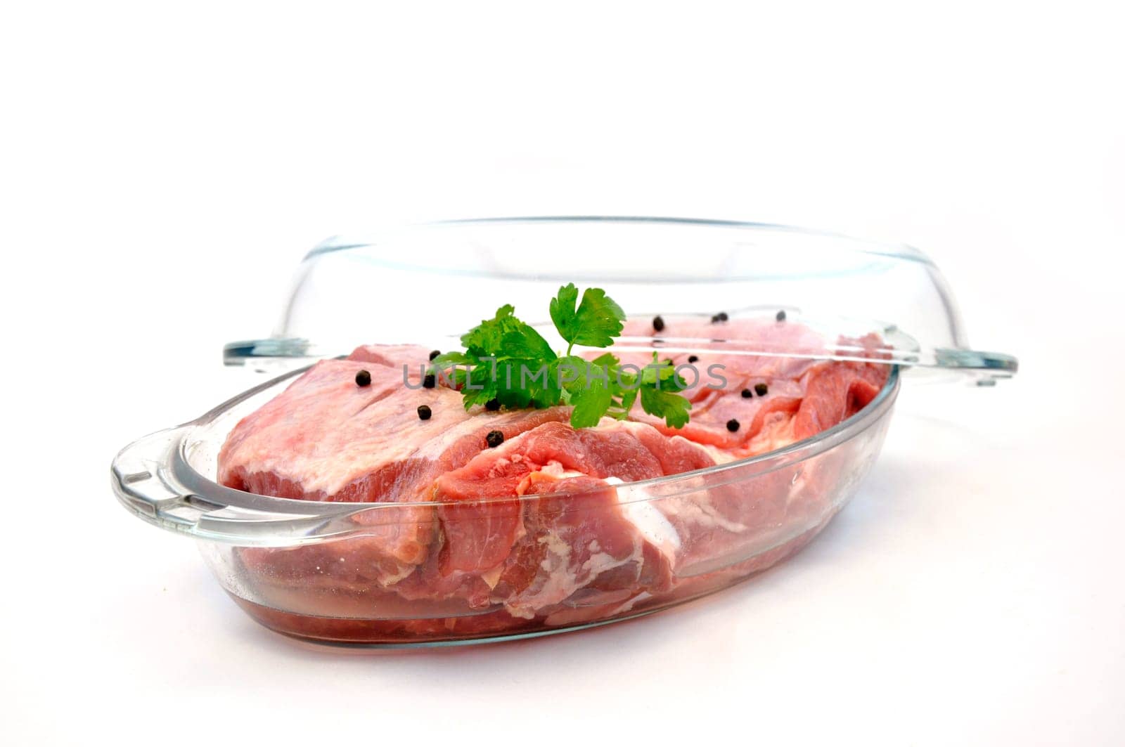 Fresh red meat with seasoning in glass pan ready to cook