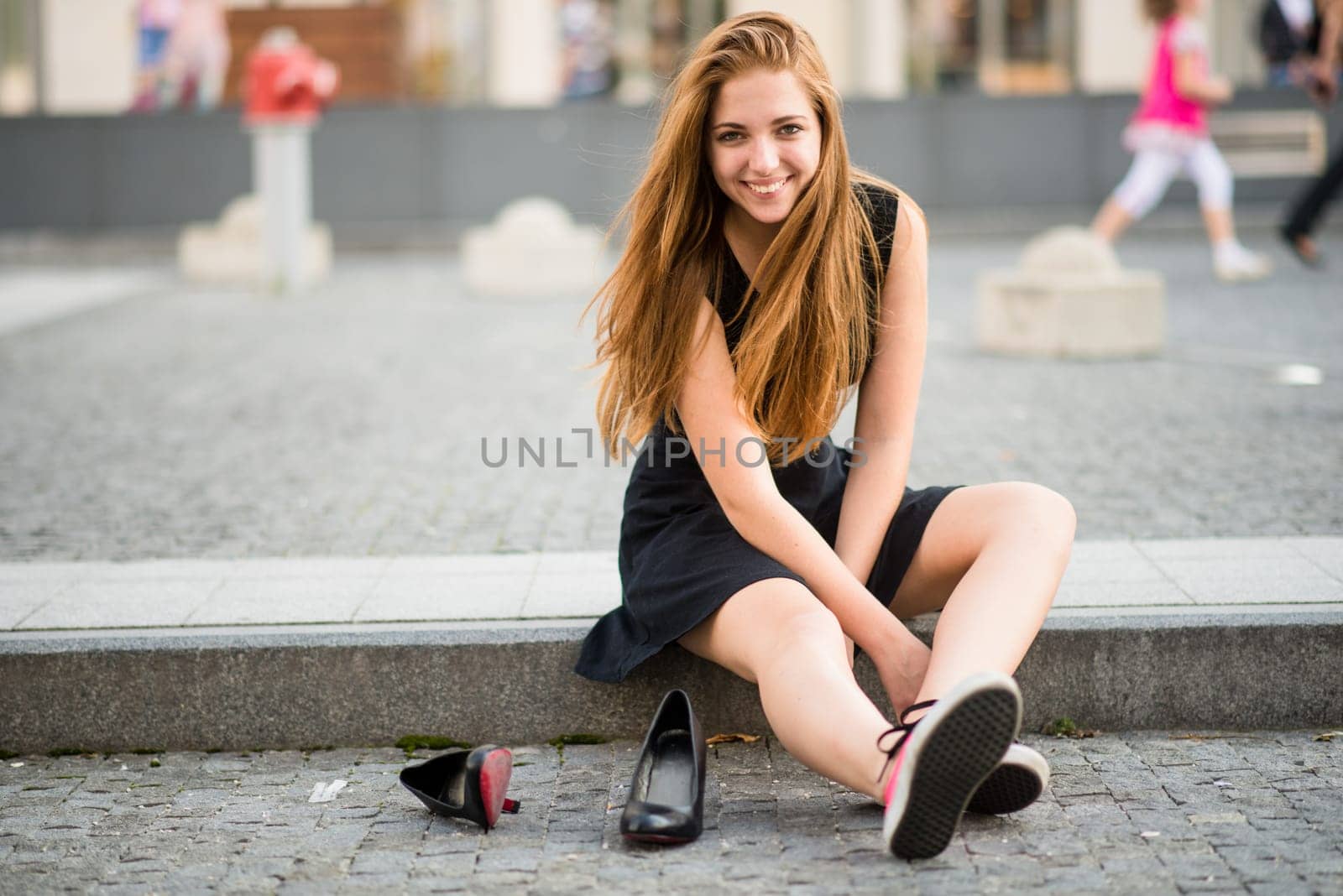 Teenager lifestyle - young woman on street in sneakers holding high heels shoes